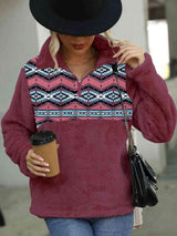 a woman in a hat and sweater holding a cup of coffee