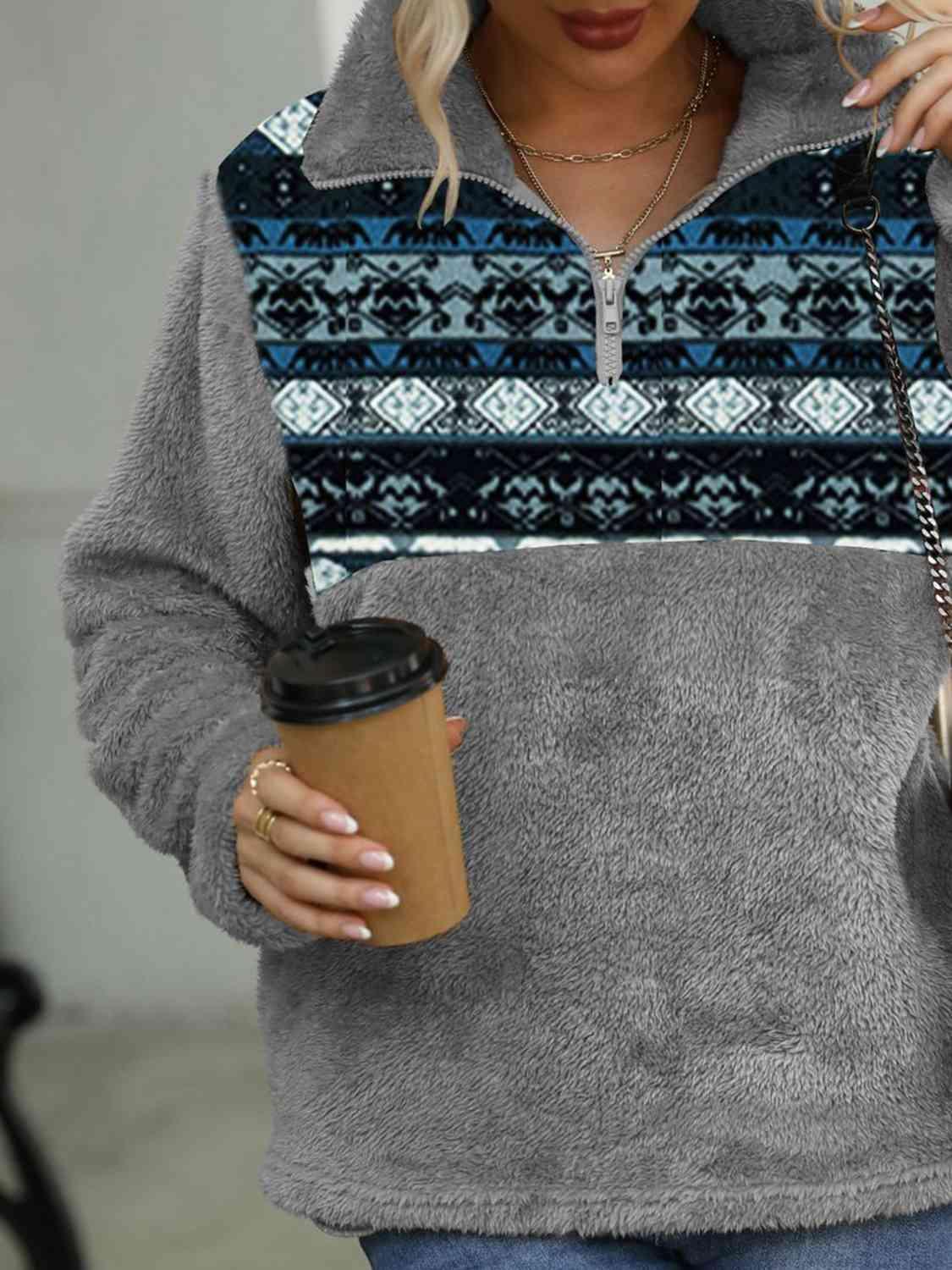 a woman with blonde hair wearing a gray sweater and holding a cup of coffee