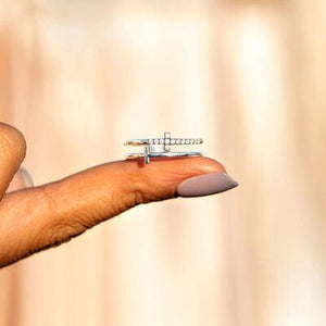 a woman's hand holding a ring with a cross on it