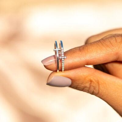 a woman's hand holding a ring with a cross on it