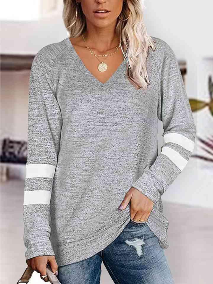 a woman wearing a grey sweater and ripped jeans