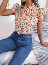 a woman sitting on a bed wearing jeans and a blouse