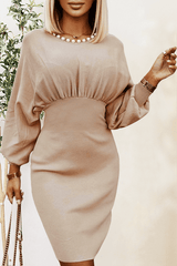 a woman in a beige dress posing for a picture