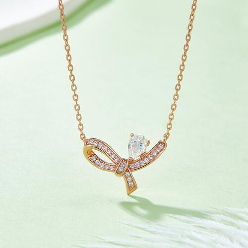 a gold necklace with a diamond bow on it