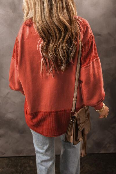 a woman in a red sweater is holding a brown purse