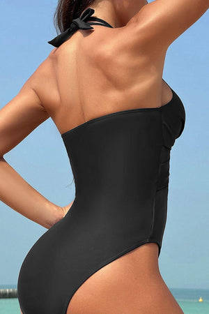 a woman in a black one piece swimsuit on the beach