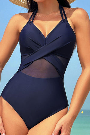 a woman in a blue one piece swimsuit on the beach