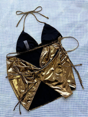 a gold and black bikini top on a blue cloth
