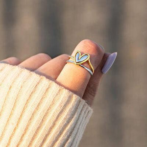 a woman's hand wearing a ring with a heart on it