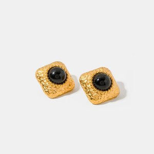 a pair of black and gold earrings on a white background