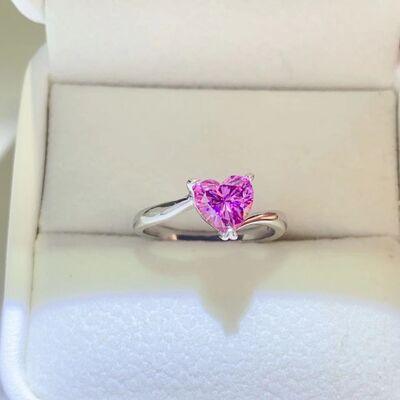 a pink heart shaped ring sitting on top of a white box