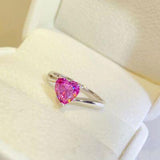 a pink heart shaped ring sitting on top of a white box