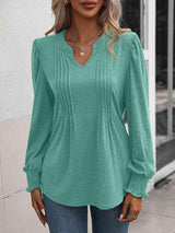 a woman wearing a green blouse and jeans