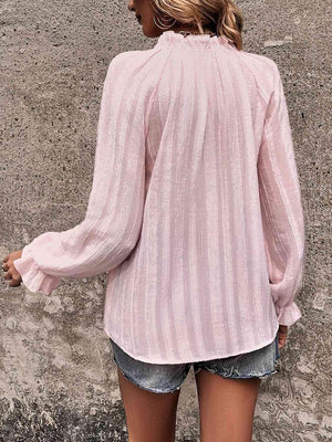 a woman wearing a pink blouse and denim shorts