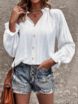 a woman wearing a white blouse and denim shorts