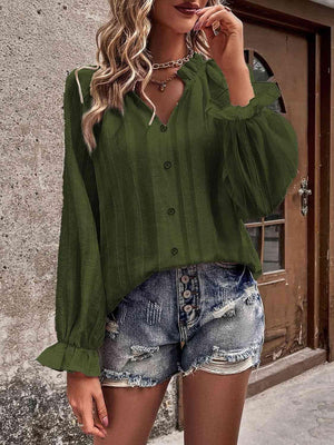 a woman wearing a green blouse and denim shorts