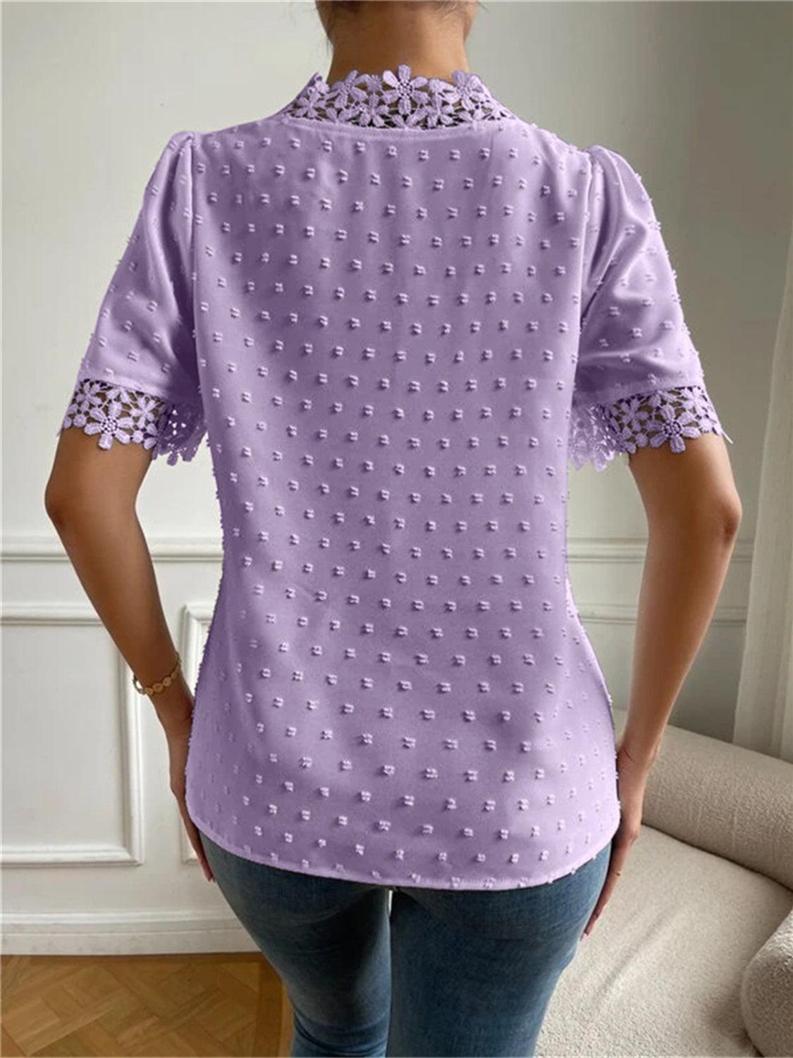 a woman standing in front of a couch wearing a purple shirt