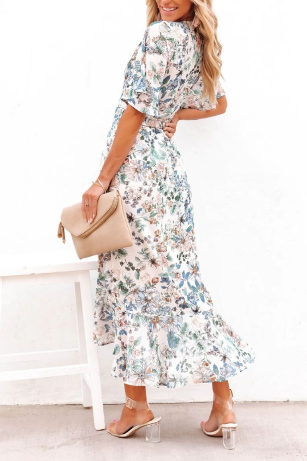 a woman in a floral dress standing on a chair