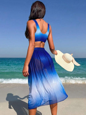 a woman in a blue dress and hat walking on the beach