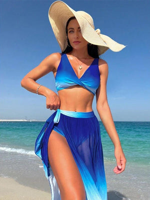 a woman in a blue bikini top and a blue skirt on the beach