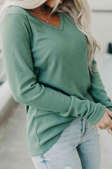 a woman wearing a green sweater and ripped jeans