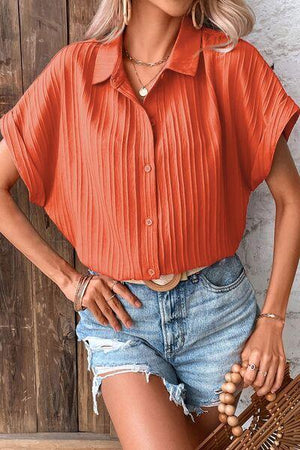 a woman wearing an orange shirt and denim shorts