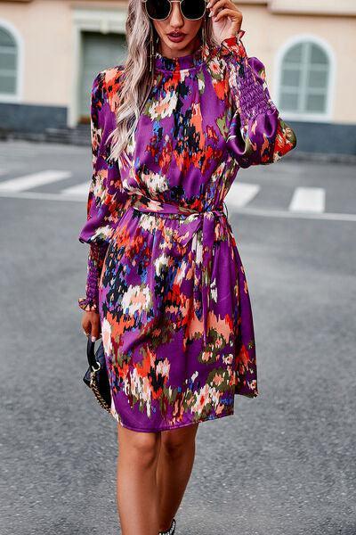 a woman wearing a purple floral dress and sunglasses