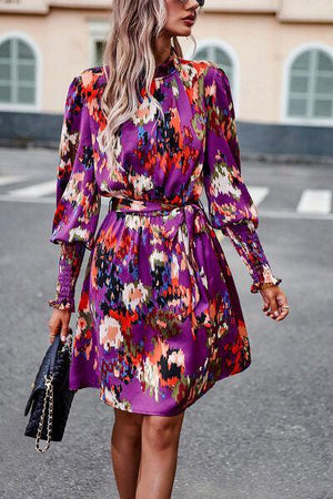 a woman in a purple floral dress is walking down the street