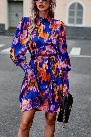 a woman in a colorful dress is standing on the street