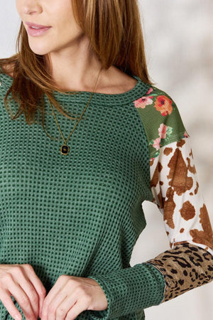 a woman wearing a green sweater with a cow print sleeve