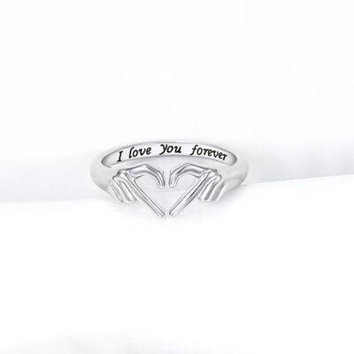 a silver ring with two hands holding a heart