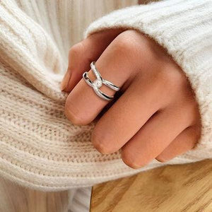 a woman wearing a white sweater and a silver ring