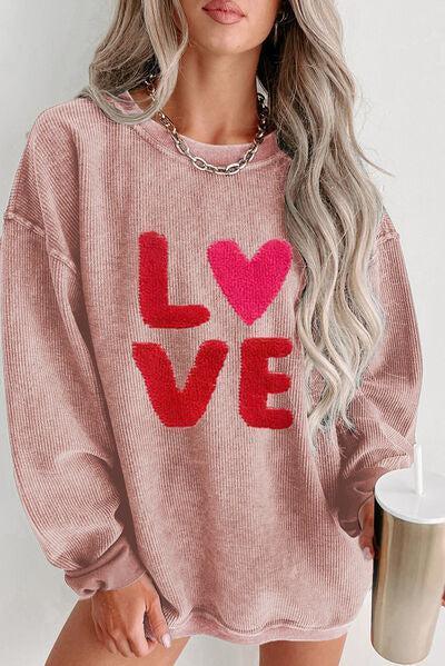 a woman wearing a pink sweater with the word love on it