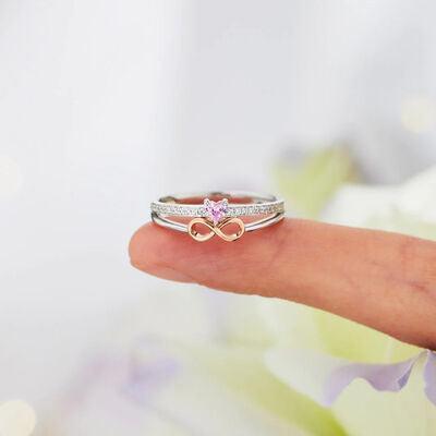 a woman's hand holding a ring with a pink diamond