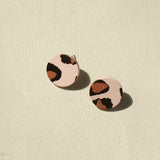 a pair of pink and brown earrings on a white surface