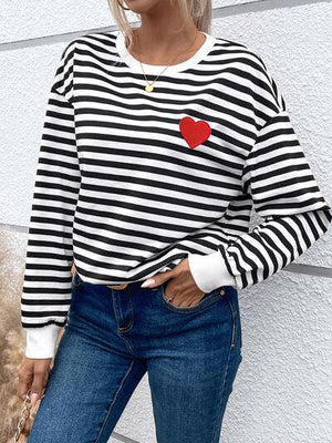 a woman wearing a black and white striped shirt with a red heart on it