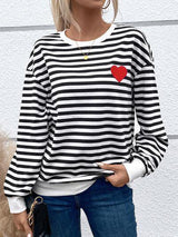 a woman wearing a black and white striped shirt with a red heart on it