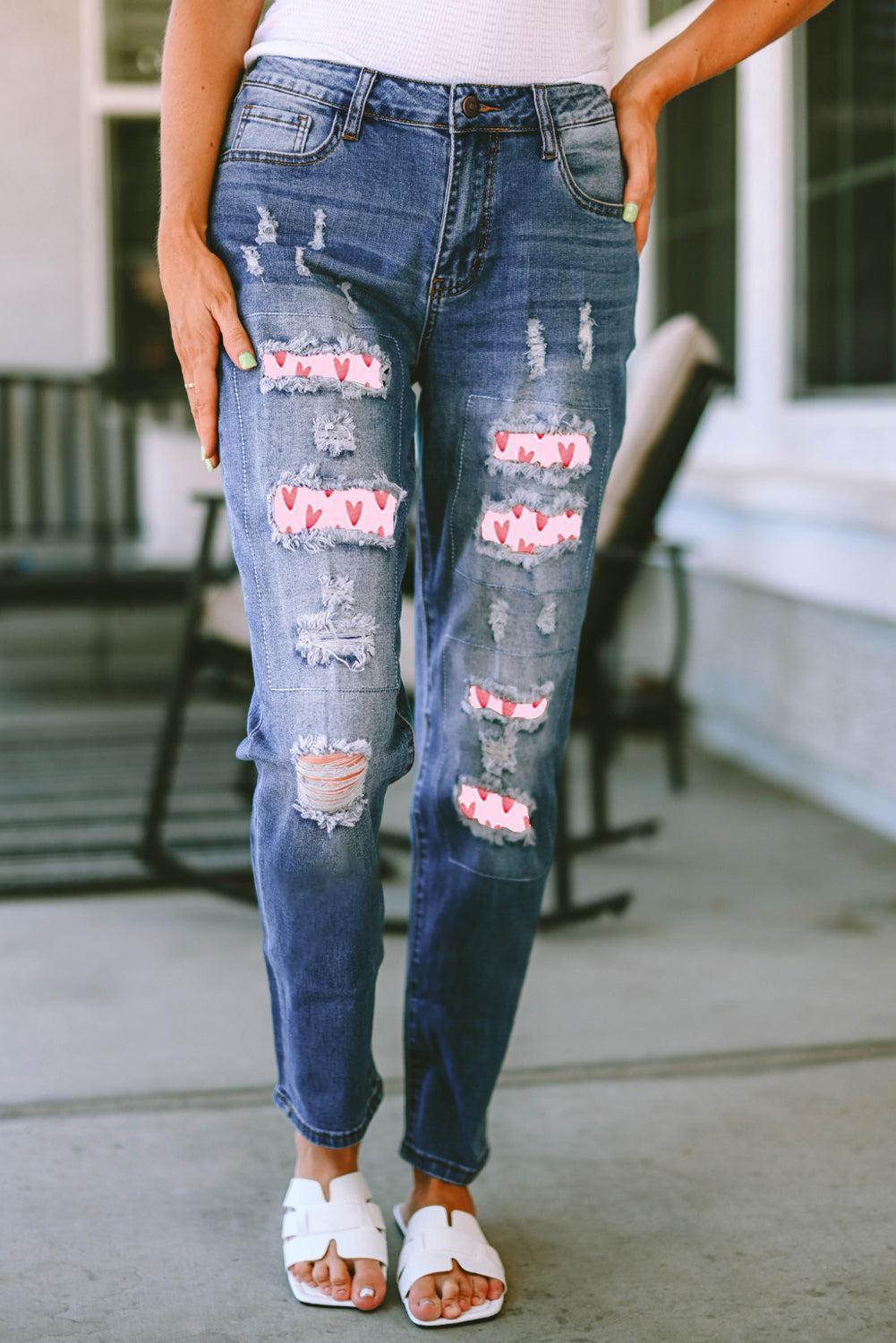 a woman standing on a sidewalk wearing ripped jeans