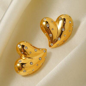 a pair of heart shaped earrings on a white cloth