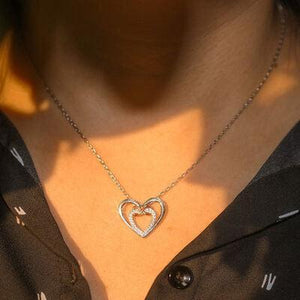 a woman wearing a necklace with a heart on it