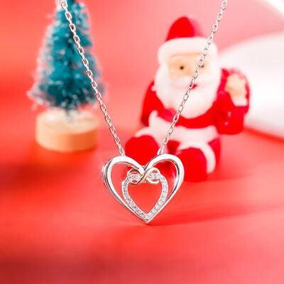 a santa clause holding a heart necklace next to a small christmas tree