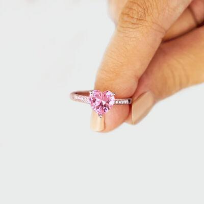 a woman's hand holding a pink heart shaped ring