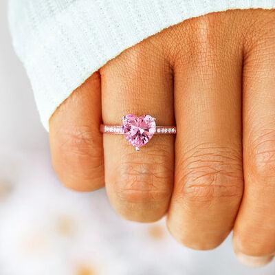 a woman's hand holding a pink heart shaped ring