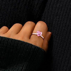 a woman's hand with a pink ring on it