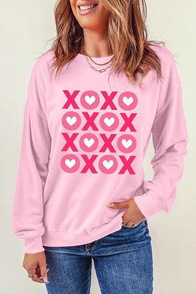a woman wearing a pink sweatshirt with hearts on it