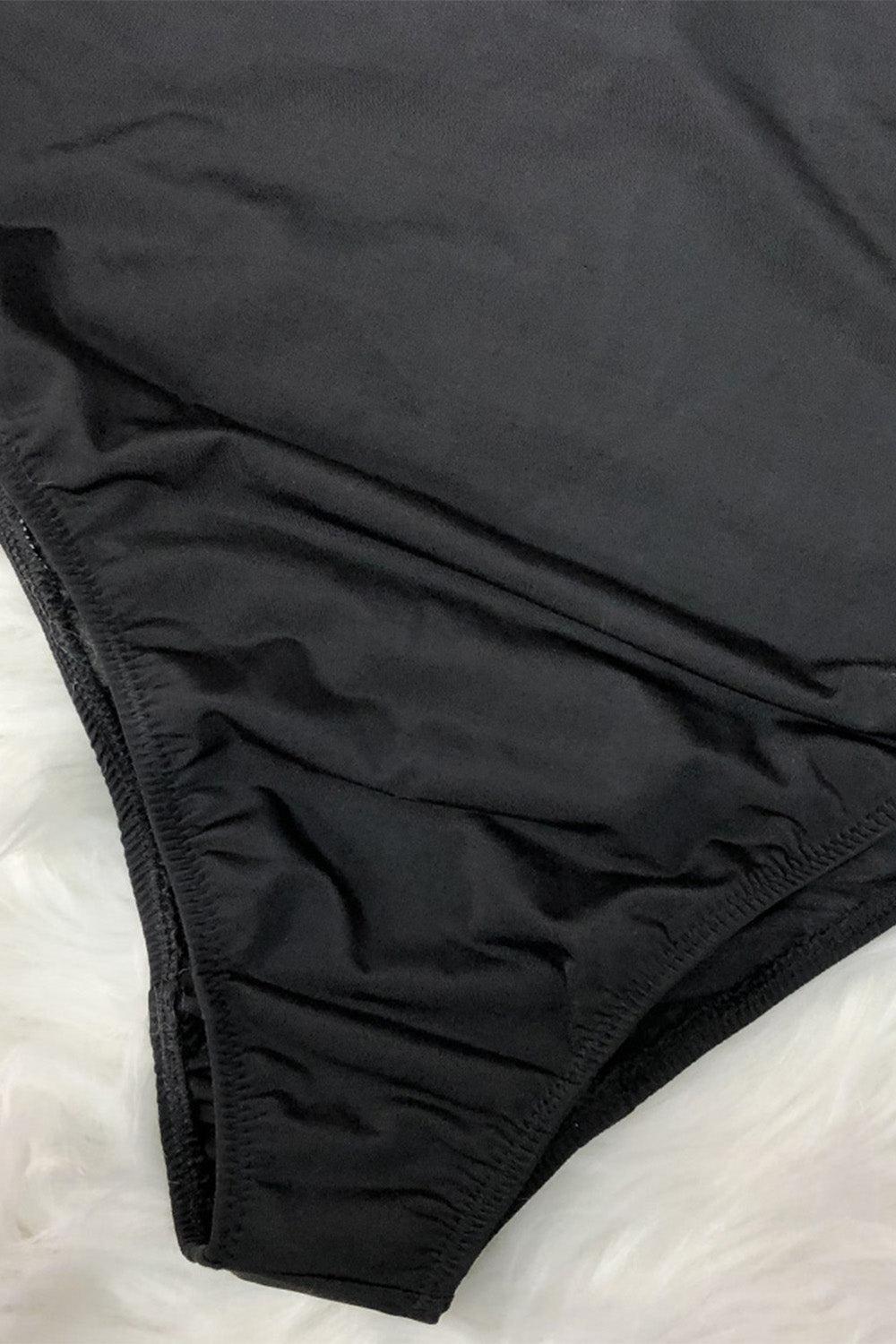 a close up of a black underwear on a bed