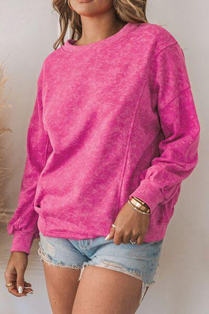 a woman wearing a pink sweater and denim shorts