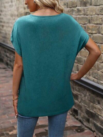 a woman wearing a green top standing in front of a brick wall