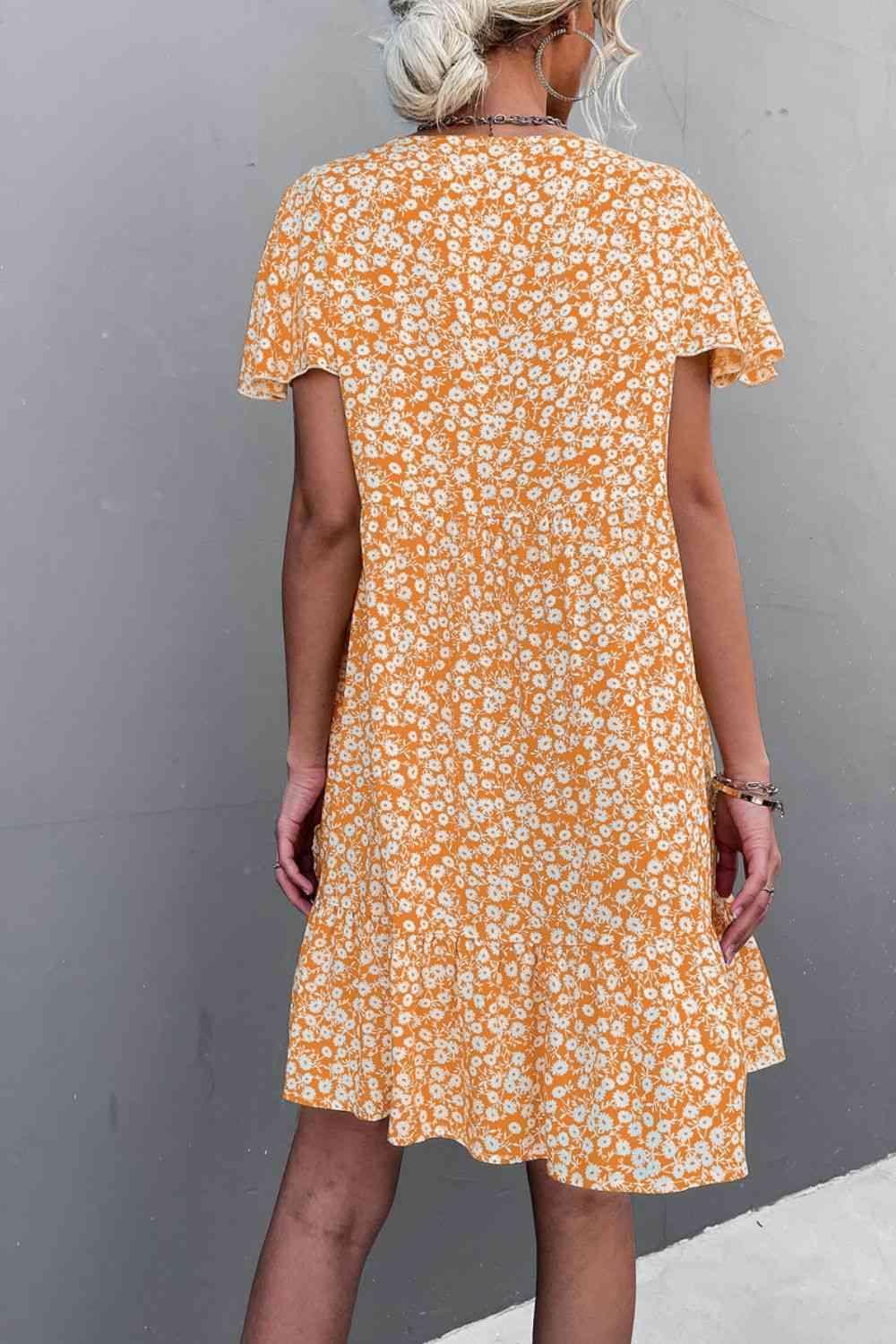 a woman in an orange and white floral dress