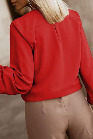 a woman wearing a red blouse and tan pants